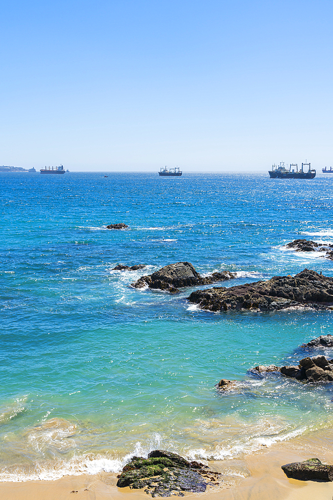 Rocky coastline and ships on sea, Caleta Abarca beach, Vina del Mar, Valparaiso Region, Chile, South America