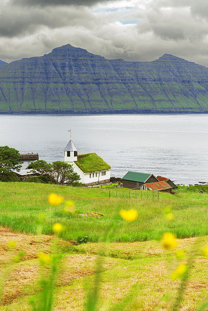 The small white Oyndarfjordur church with grass on top of the roof (turf roof) facing the ocean, Runavikar municipality, Eysturoy island, Faroe islands, Denmark, Northern Europe, Europe