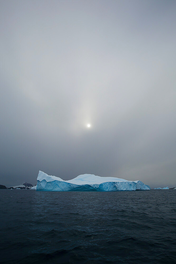 Obscure sun hovering over iceberg. Antarctic Peninsula, Antarctica