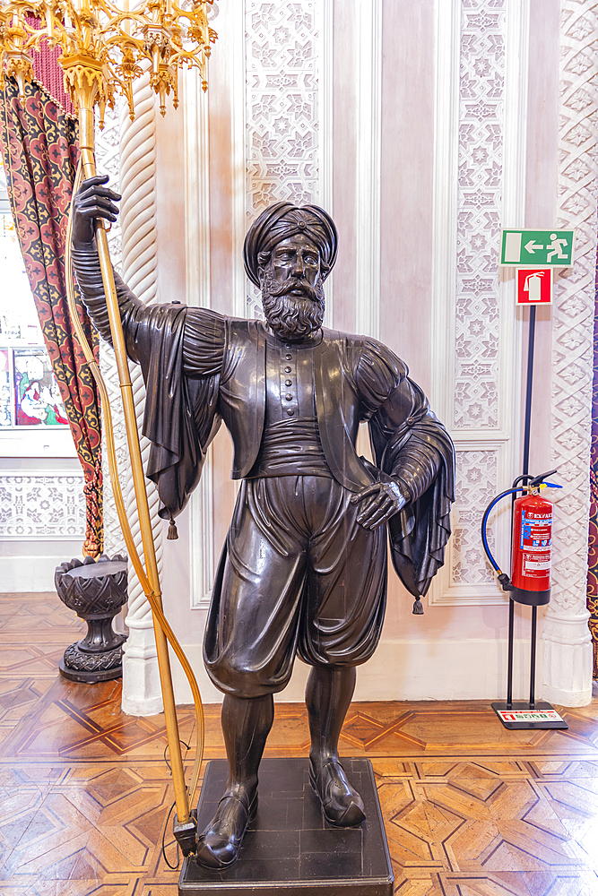 Europe, Portugal, Sintra. April 17, 2022. Sculpture of a Moor in the Park and National Palace of Pena, a UNESCO World Heritage Site in Sintra.