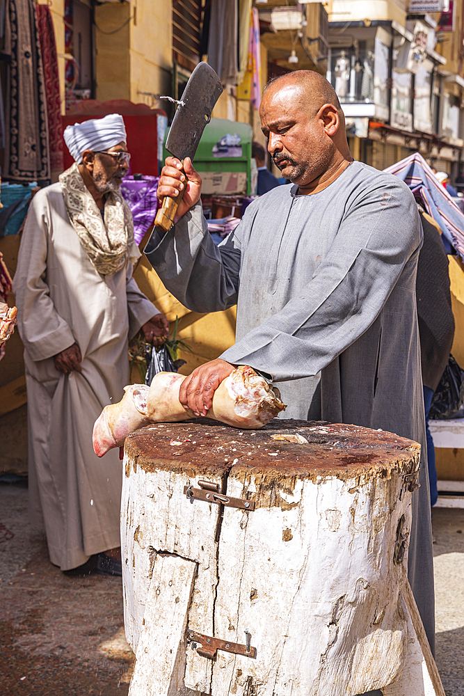 Thebes, Luxor, Egypt. February 24, 2022. Butcher chopping a cow foot on a outdoor butcher block.