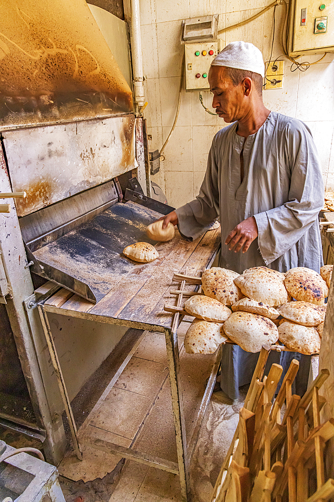 Thebes, Luxor, Egypt. February 24, 2022. Baker making pita bread with an automated oven.