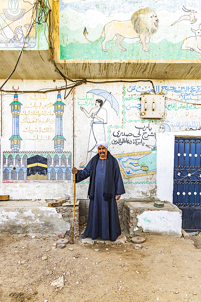 Thebes, Luxor, Egypt. February 26, 2022. Man standing in front of contemporary murals on in Luxor.