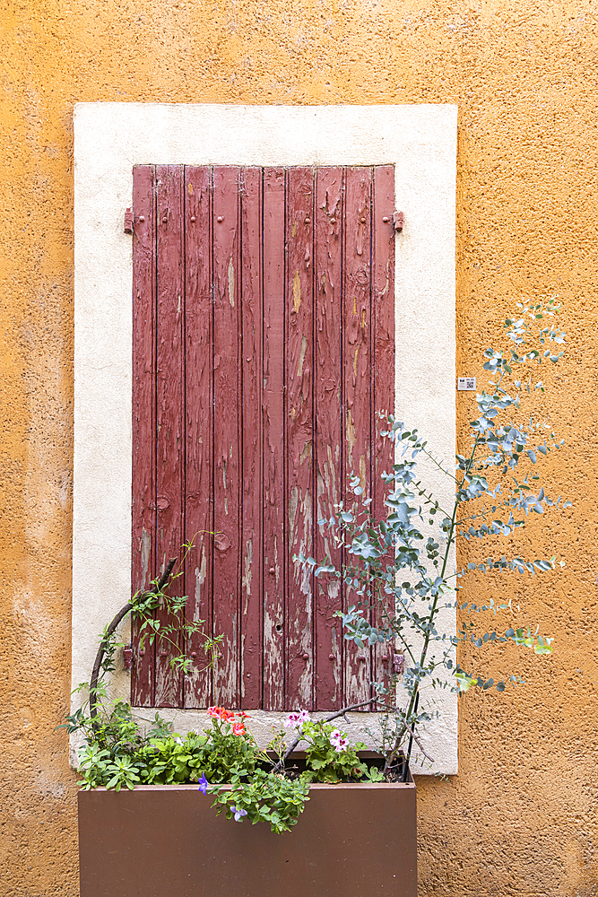 L'Isle-sur-la-Sorgue, Avignon, Vaucluse, Provence-Alpes-Cote d'Azur, France. Red peeling paint on wooden window shutters.