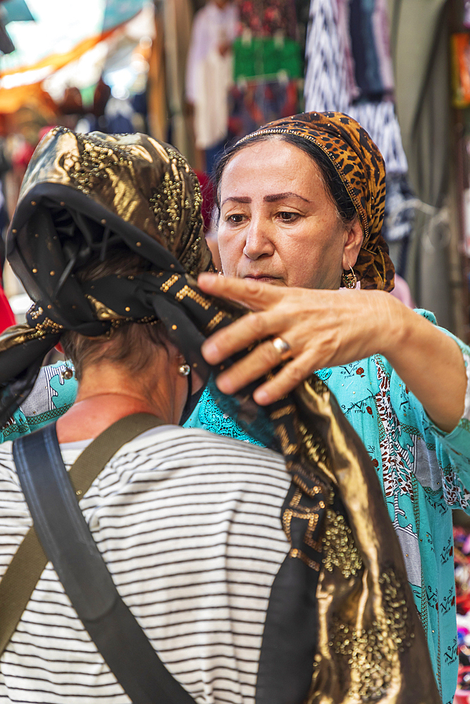 Kulob, Khatlon Province, Tajikistan. August 13, 2021. Woman being fitted with a head scarf in the market in Kulob. Editorial Use Only