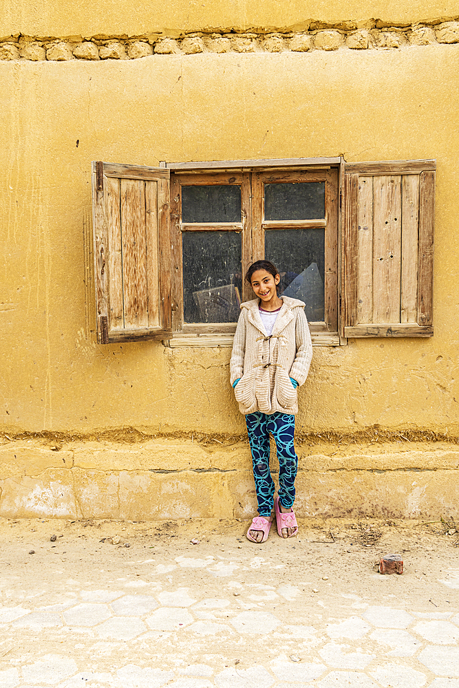 Faiyum, Egypt. February 19, 2022. Girl leaning on a building in the village of Faiyum.