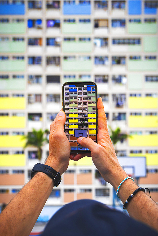A tourist takes picture with his phone of the Choi Hung Estate, Kowloon, Hong Kong island, Hong Kong, China, Asia