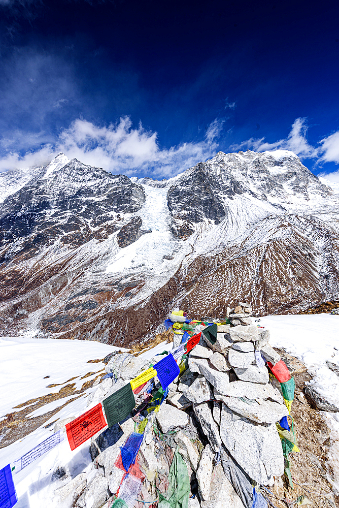 Vertical View of Prayer Flags and Stone Cairn on Snow-Draped Kyanjin Ri Summit Overlooking Langtang Glacier and Himalayan Peaks