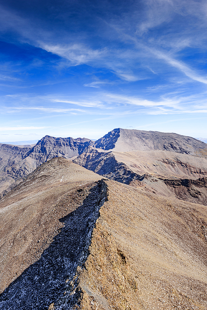 View from the summit of pico de la veleta over mountain ridges leading towards Mulhacen and Alcazaba in the Sierra Nevada, Spain