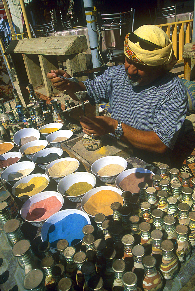 Man pouring colored sands into a decorative bottle, Jordan, Middle East