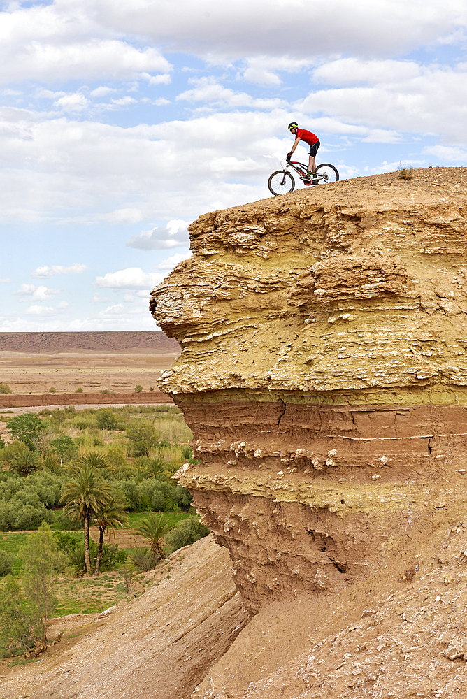 Cyclist on a promontory facing the Ksar of Ait-Ben-Haddou, Ounila River valley, Ouarzazate Province, region of Draa-Tafilalet, Morocco, North West Africa