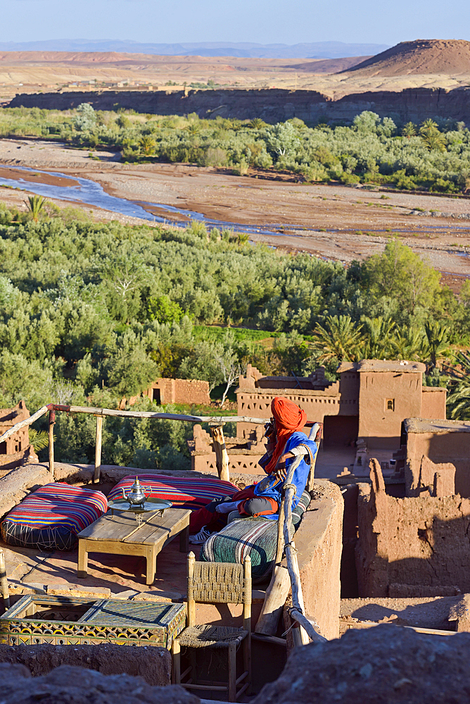 Man sitting on the terrace of a cafe overlooking the Ksar of Ait-Ben-Haddou, Ounila River valley, Ouarzazate Province, region of Draa-Tafilalet, Morocco, North West Africa