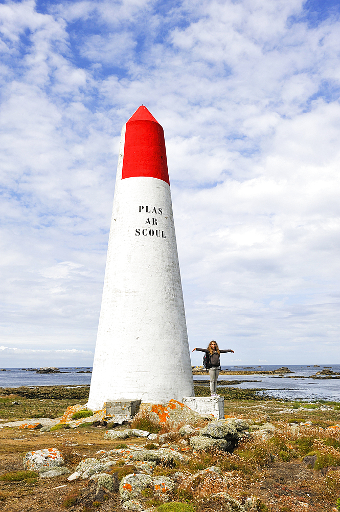 Young girl standing beside a seamark on Ile de Sein,off the coast of Pointe du Raz,Finistere department,Brittany region,west of France,western Europe