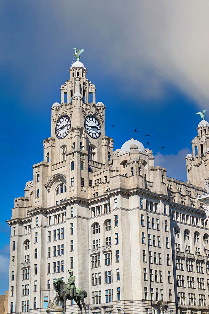 The image shows the Liver Building with ornate architecture, clock towers topped with Liver Birds, and a statue of a mounted figure in Liverpool, UK.