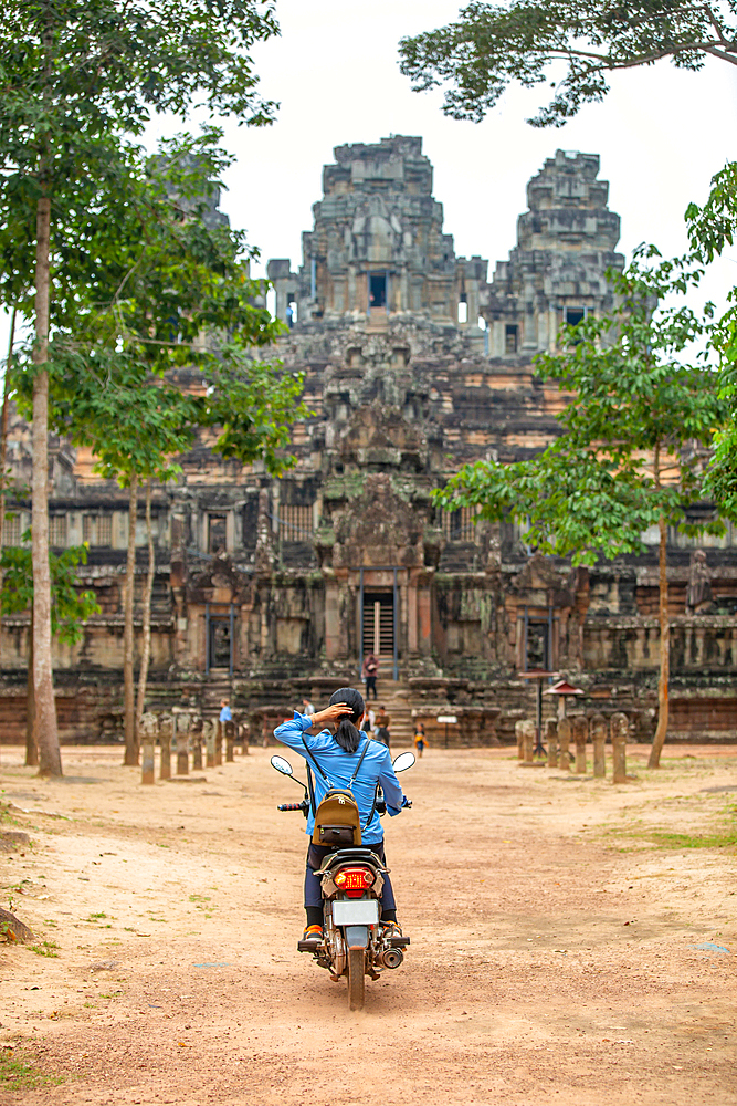 A unidentifed woman riding a scooter towards Banteay Kdei temple in Angkor complex, UNESCO World Heritage Site, Cambodia, Indochina, Southeast Asia, Asia