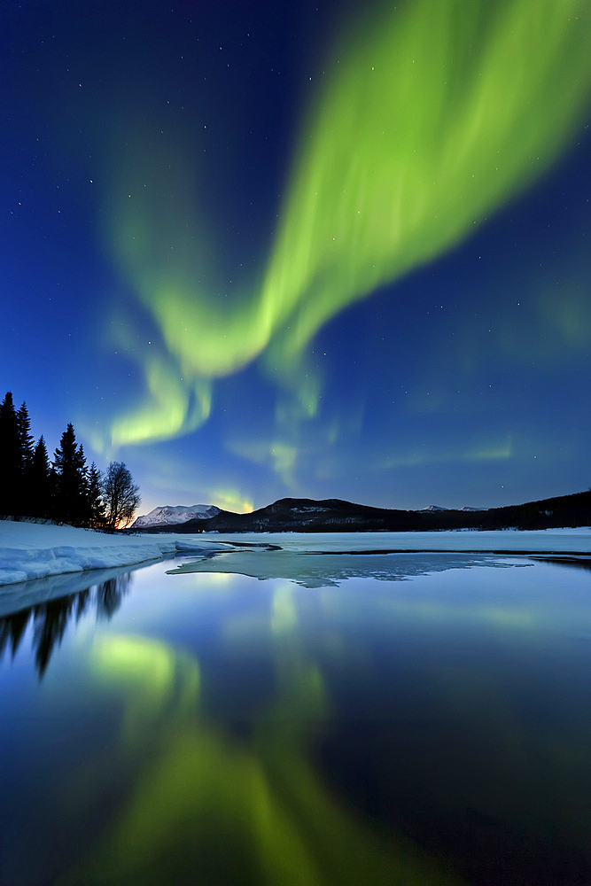 Aurora borealis over Sandvannet Lake in Troms County, Norway. Auroras are the result of the emissions of photons in the Earth's upper atmosphere.
