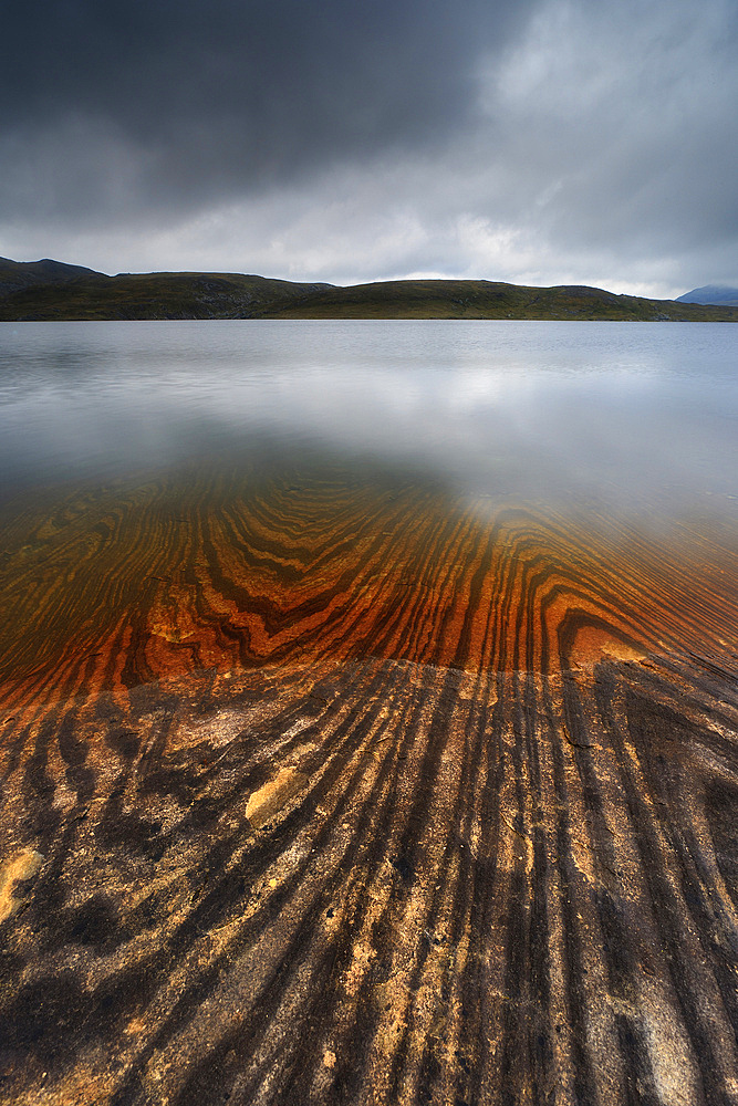 Geology lines in Sandvannet Lake, Nordland County, Norway. The Glomfjord Mountains are visible on the horizon.