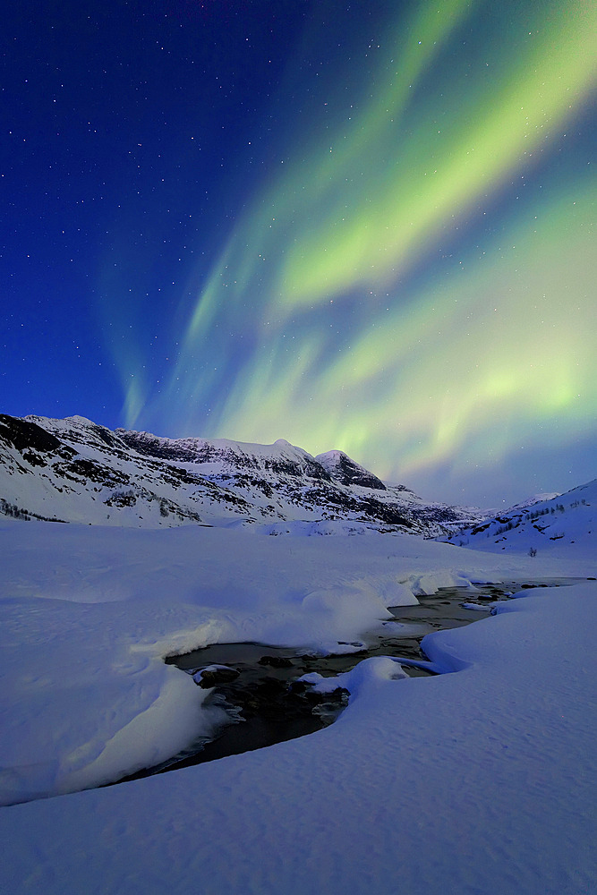 Aurora Borealis over Skittendalstinden in Troms County, Norway. Auroras are the result of the emissions of photons in the Earth's upper atmosphere.