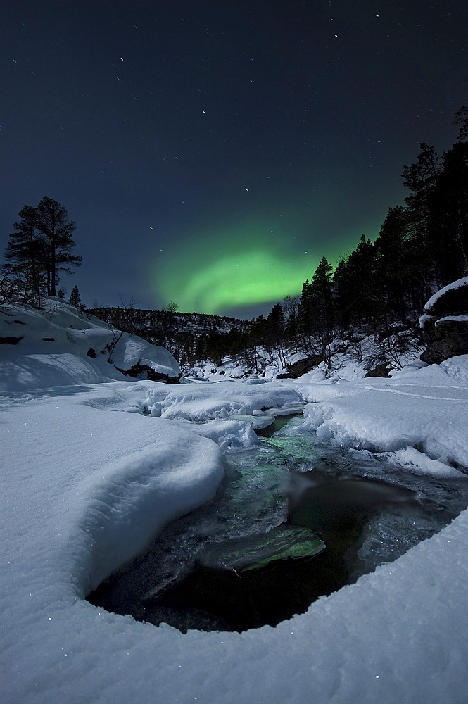 Aurora Borealis over Tennevik River in Norway. Auroras are the result of the emissions of photons in the Earth's upper atmosphere.