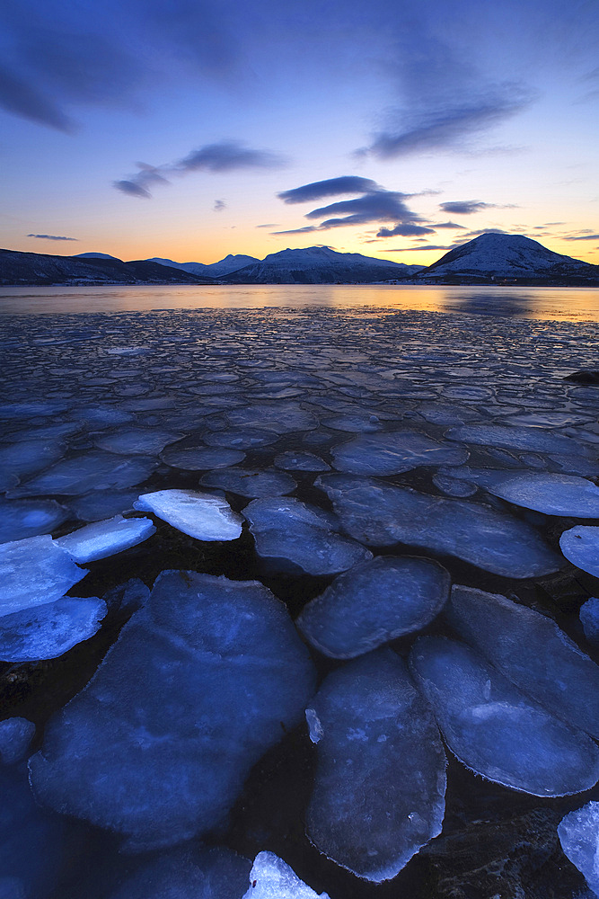 A rare sight in Tjeldsundet, Troms County, Norway. Ice flakes drifting in the sunset looking towards the mountains on Tjeldoya Island.