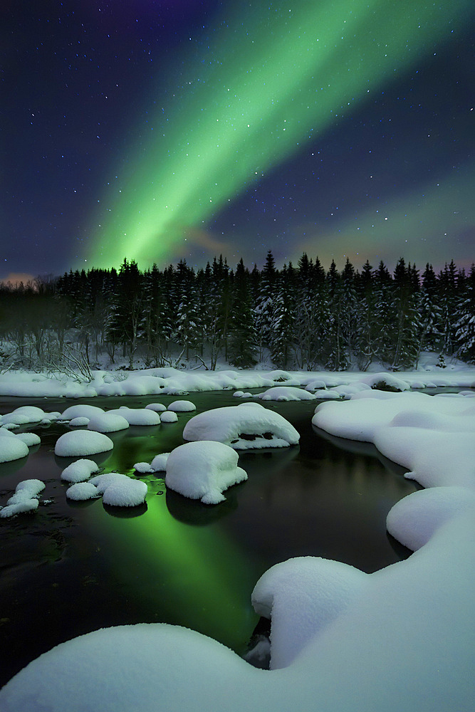Aurora Borealis over Tennevik River in Troms County, Norway. Auroras are the result of the emissions of photons in the Earth's upper atmosphere.