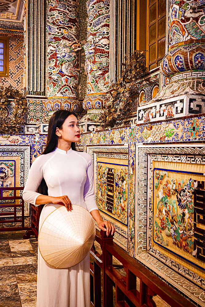 Woman in a white ao dai dress looking at carvings, Khai Dinh Tomb, Hue, Central Vietnam. (MR)