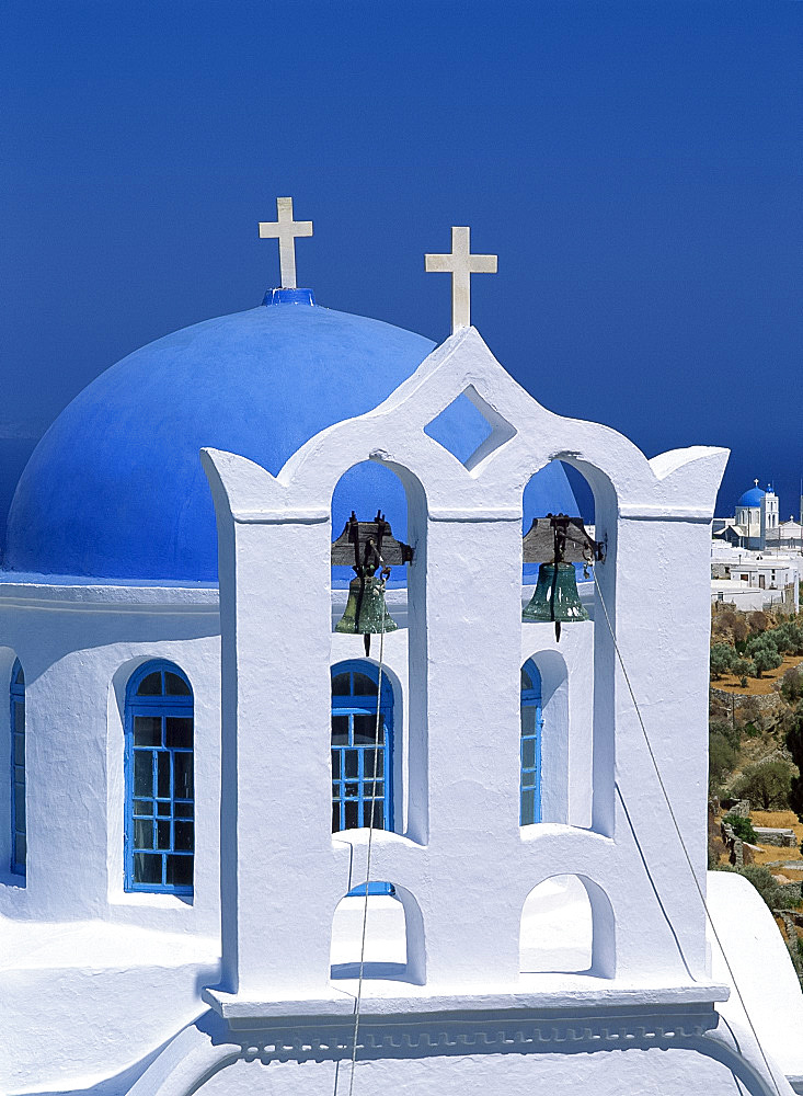 Close-up of white walls and bells in bell tower with blue dome behind at a church in Apollonia, on Sifnos, Cyclades, Greek Islands, Greece, Europe