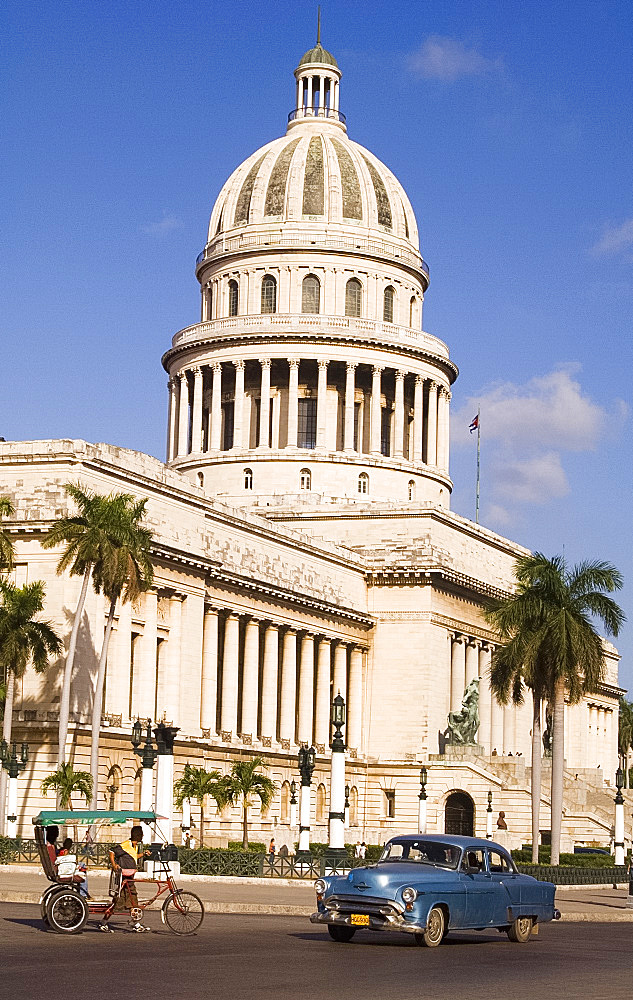 A 1950s car and rickshaw pass the Capitolio in central Havana, Cuba, West Indies, Caribbean, Central America