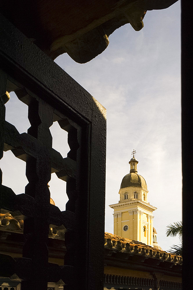 The belltower of Catedral de la Anuncion seen through the wooden screens of Casa de Diego Velazquez, Santiago de Cuba, Cuba, West Indies, Central America