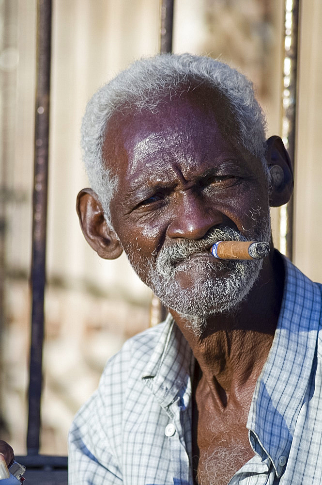 An old Cuban man smoking a cigar in Trinidad, Cuba, West Indies, Central America