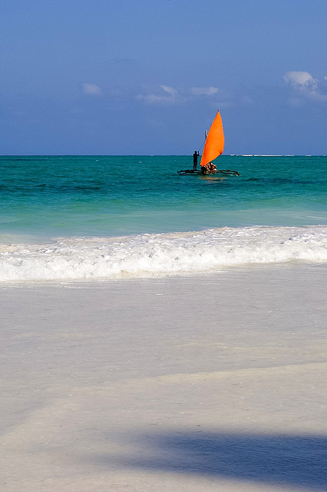 A traditional wooden dhow with an orange sail in the Indian Ocean, Paje, Zanzibar, Tanzania, East Africa, Africa