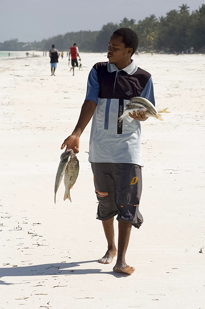 A man walking along the beach with his catch of the day, Jambiani, Zanzibar, Tanzania, East Africa, Africa