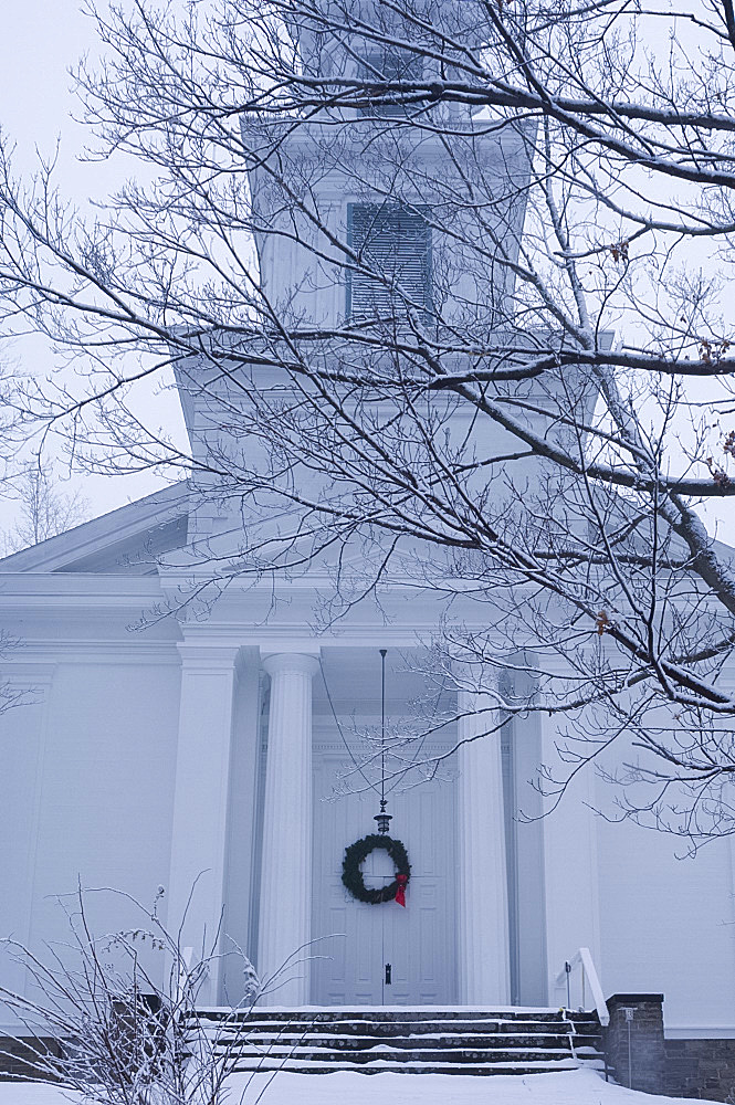 A traditional style wooden church with a Christmas wreath on the front door surrounded by snow, Rensselaerville, New York State, United States of America, North America