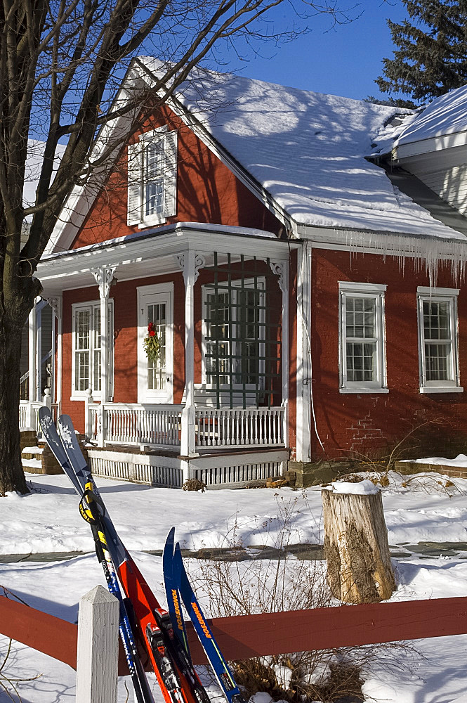 Skis leaning on a fence in front of a colourful red house in Stowe, Vermont, New England, United States of America, North America