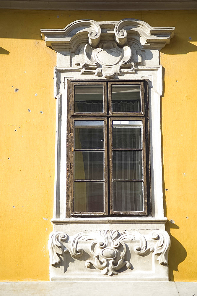 An old window surrounded by ornate carving in the Castle Hill section of Buda, Budapest, Hungary, Europe