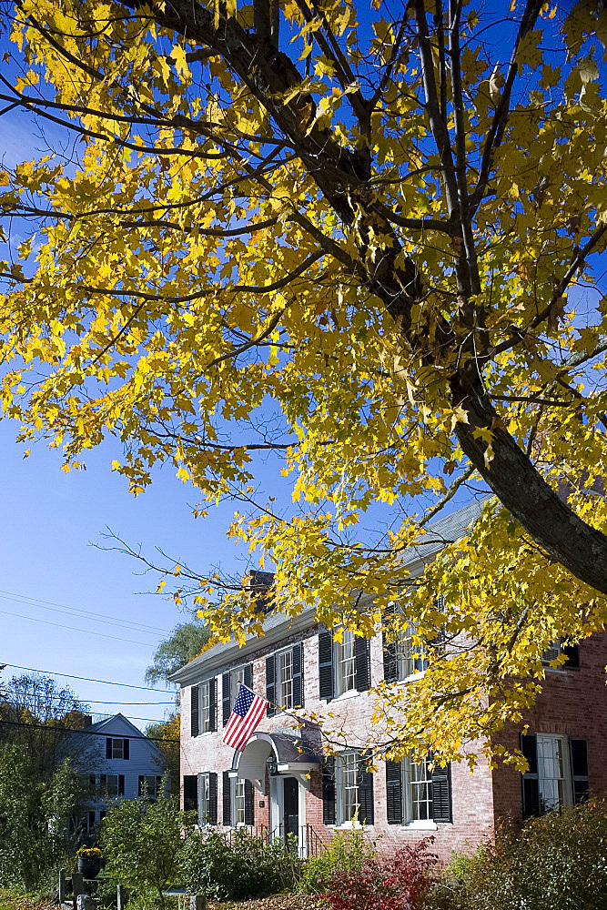 An old brick house displaying an American flag and surrounded by autumn foliage in Townshend, Vermont, New England, United States of America, North America