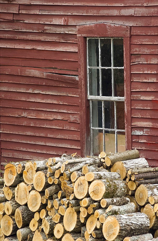 Logs piled next to a barn window in Peacham, Vermont, New England, United States of America, North America