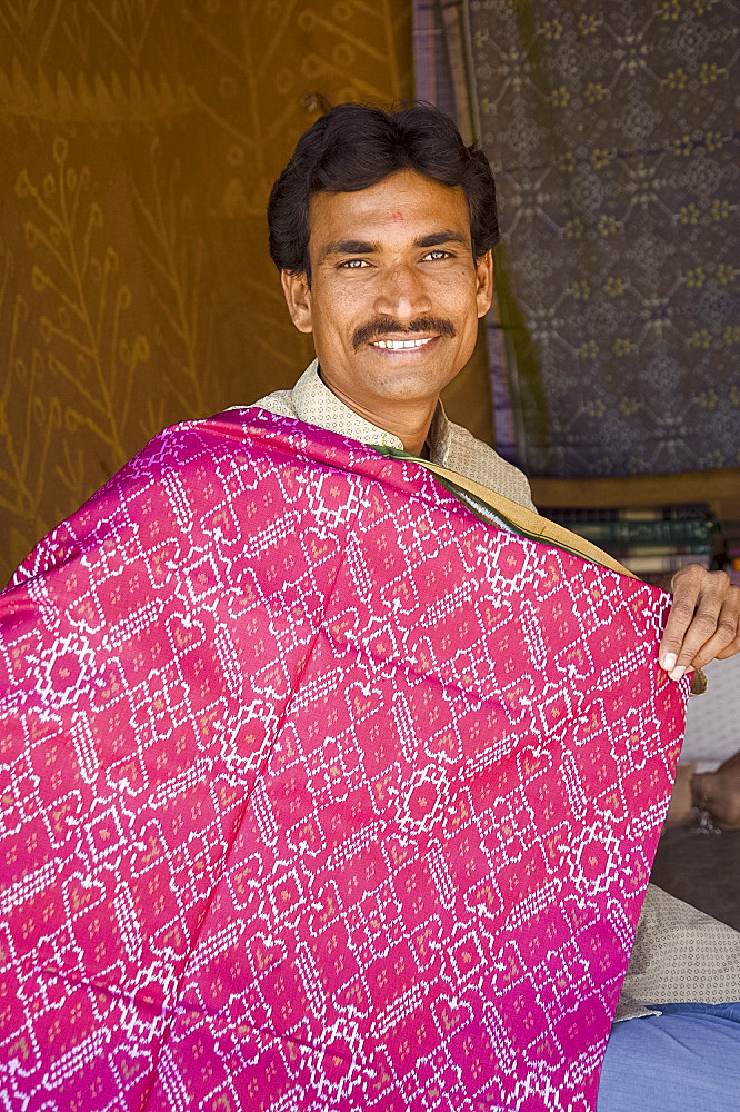 A man showing off colourful hand woven sari material at the Shilpgram Craftsmen's Village, Udaipur, Rajasthan, India, Asia