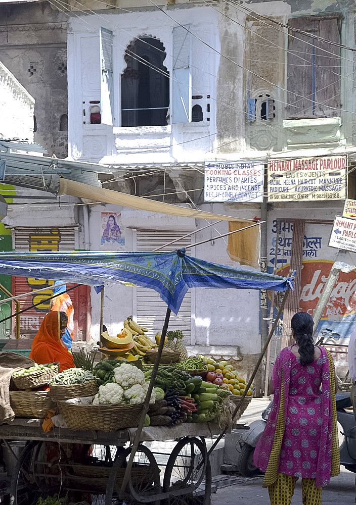 A woman selling fruit and vegetables at a stand in the old part of Udaipur, Rajasthan, India, Asia