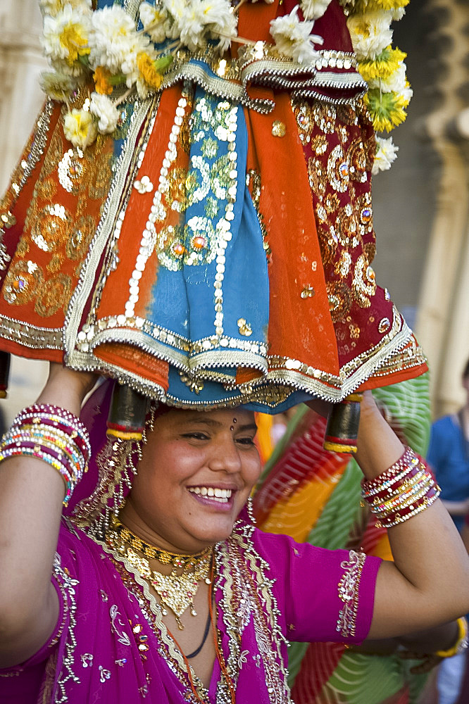 Sari clad woman carrying idol at the Mewar Festival in Udaipur, Rajasthan, India, Asia