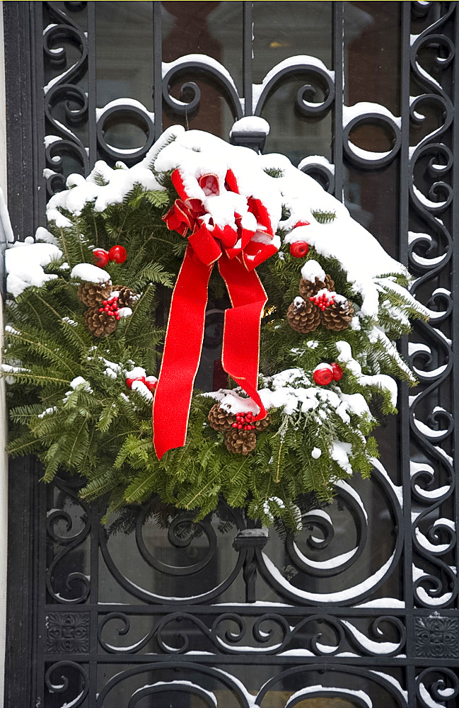 A snow covered Christmas wreath on a door on the East Side of Manhattan, New York City, New York State, United States of America, North America