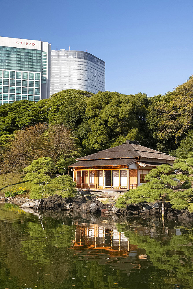 A modern highrise hotel above the Tsubame-no-ochaya, a tea house on a lake in the Hama-rikyu Gardens, Tokyo, Honshu, Japan, Asia