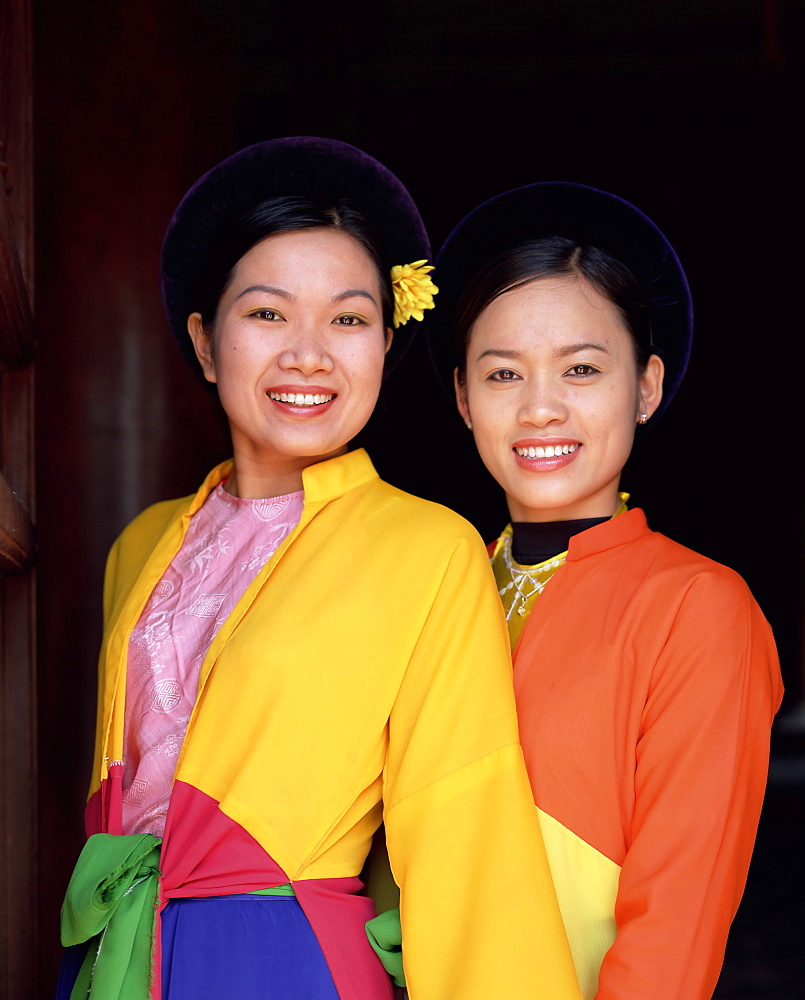 Two smiling Vietnamese women in traditional dress, smiling and looking at the camera, Temple of Literature, Hanoi, North Vietnam, Vietnam, Indochina, Southeast Asia, Asia