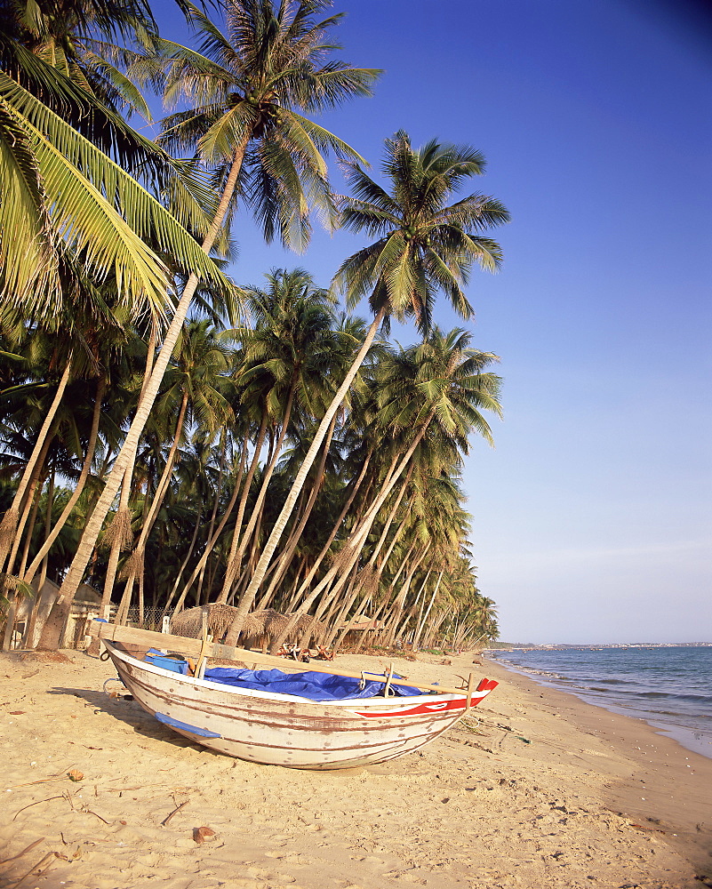 Small boat on palm fringed beach, Mui Ne beach, south-central coast, Vietnam, Indochina, Southeast Asia, Asia