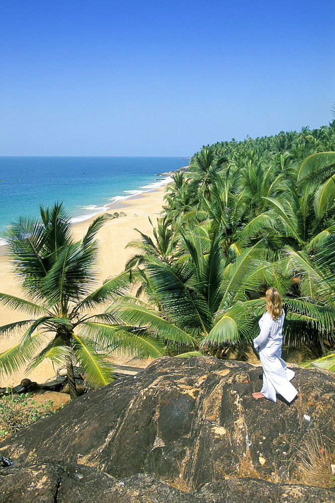 Woman looking over coconut palms to the beach, Kovalam, Kerala state, India, Asia