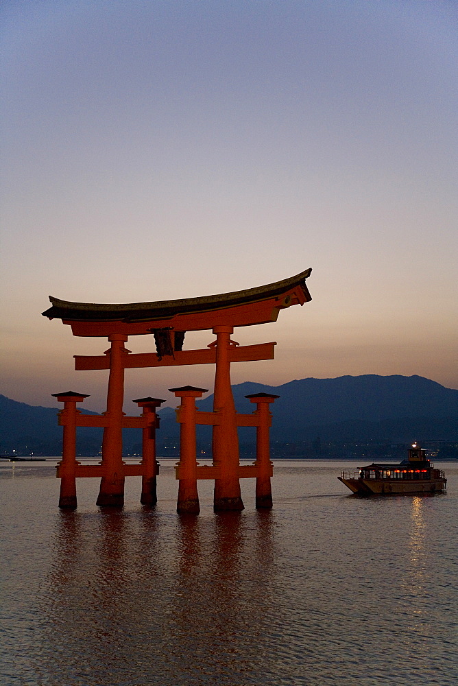 Vermillion coloured 'floating' torii gate (O-torii gate) illuminated at dusk, a Shinto shrine gate, UNESCO World Heritage Site, Itsuku-shima, Miyajima, Hiroshima, Honshu Island, Japan, Asia