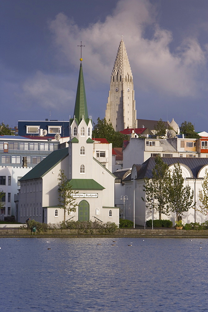 The tin-clad Frikirkjan i Reykjavik church and Hallgrimskirkja rising above the city viewed across Lake Tjorn, Reykjavik, Iceland, Polar Regions