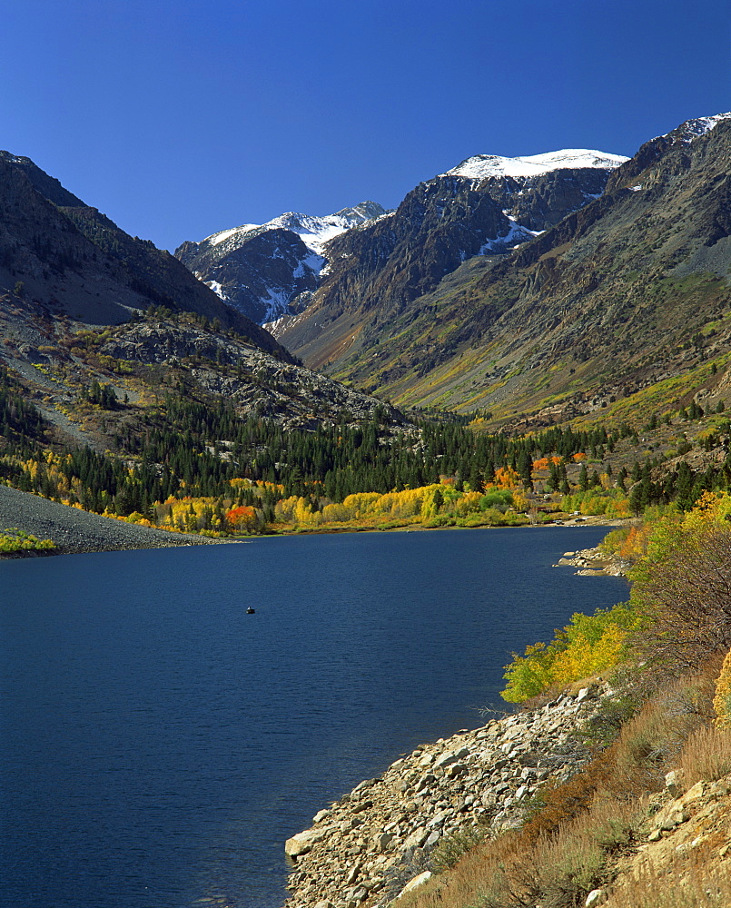 Landscape of June Lake with trees in fall colours and snow capped mountains in the background, in California, United States of America, North America