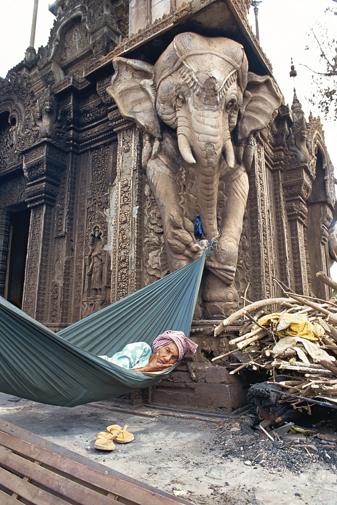 Homeless woman in a hammock attached to an elephant carving in a central temple in Phnom Penh, Cambodia, Indochina, Southeast Asia, Asia