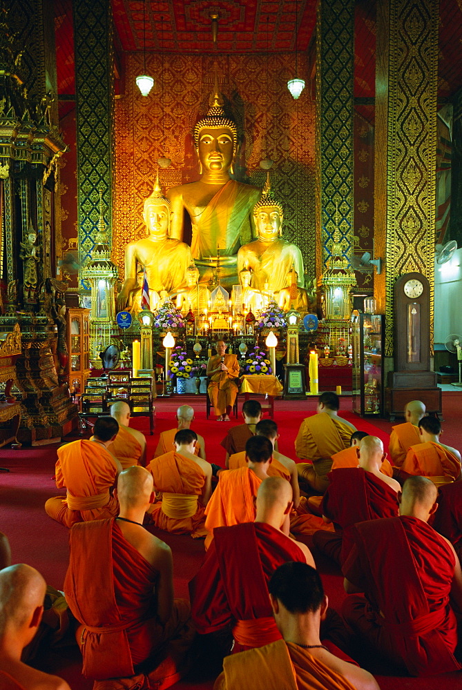 Monks seated inside temple, Wat Phra That Hariphunchai, Lamphun, northern Thailand, Asia